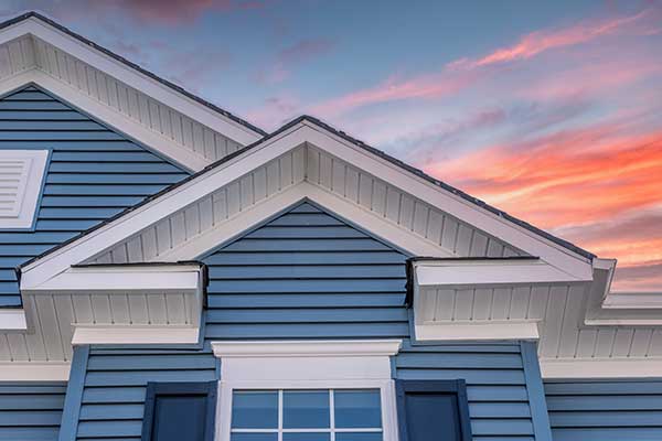 Top half of home with blue siding at sundown