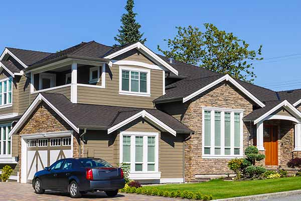 Mid-class residential brown home with a dark gray shingle roof