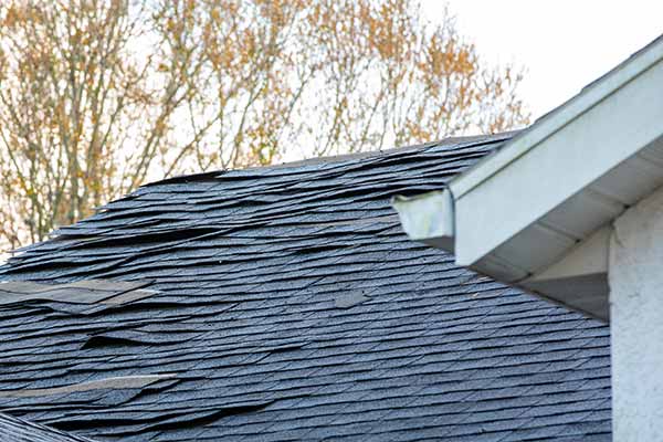 Residential roof with loose shingles about to fall off due to storm damage